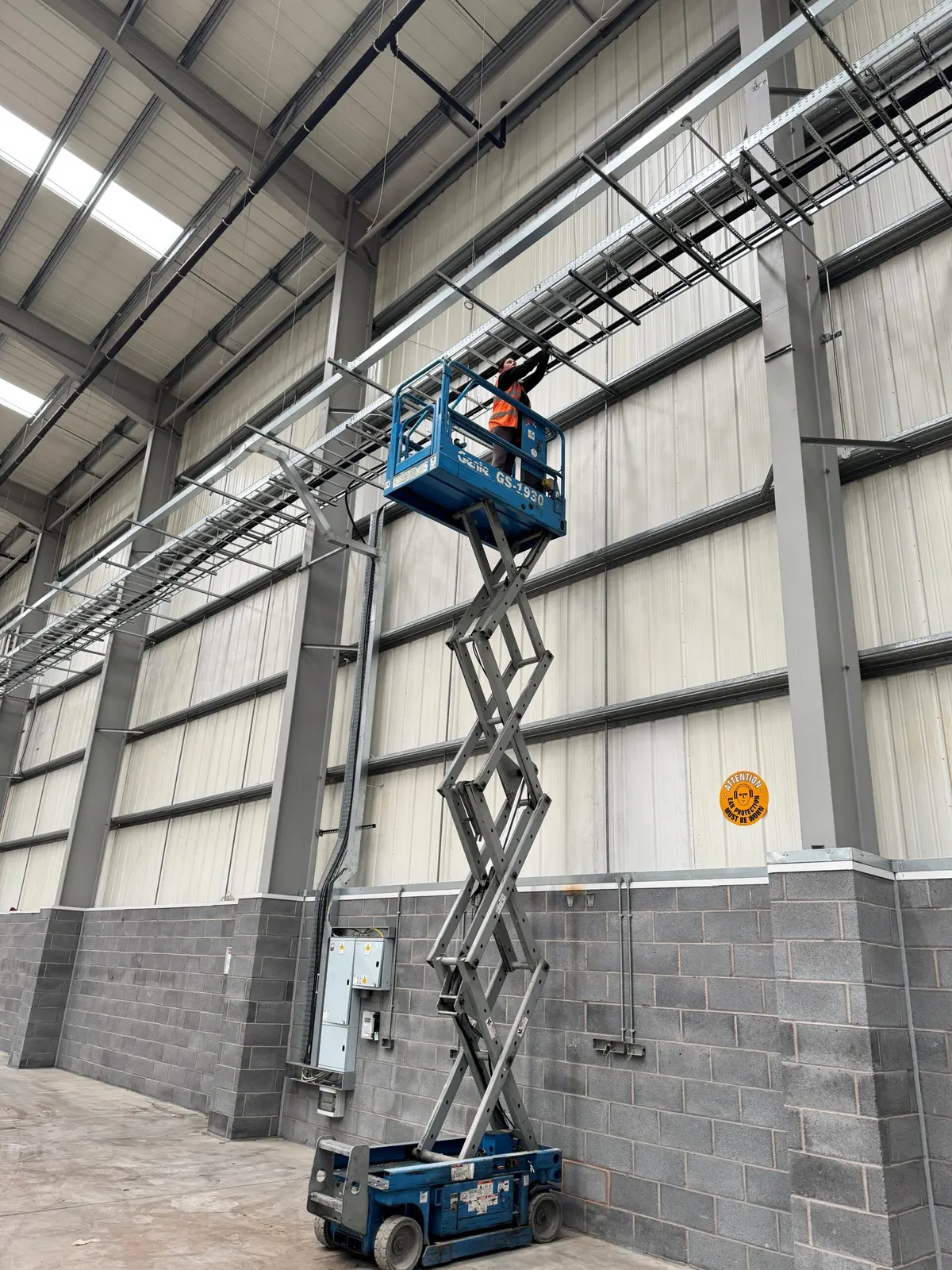 Operative on a scissor lift working on cable tray runs high on the internal wall