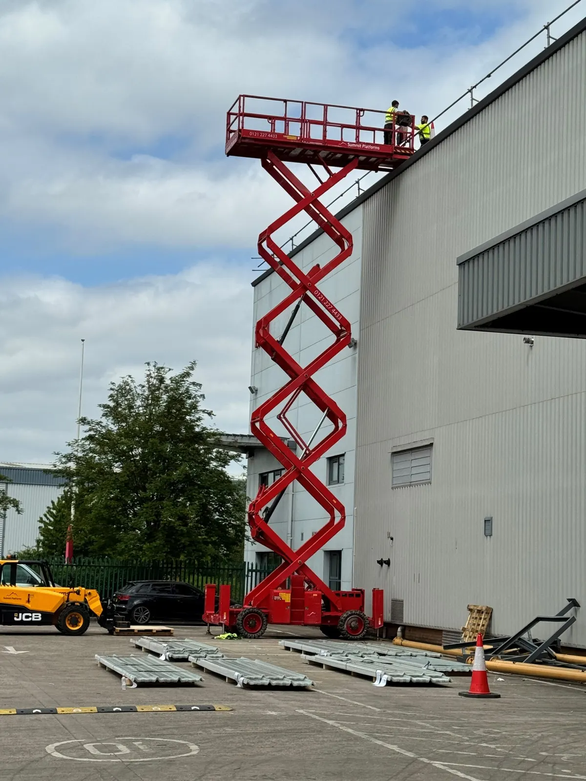Operatives working from a scissor lift at roof level on the outside of the building