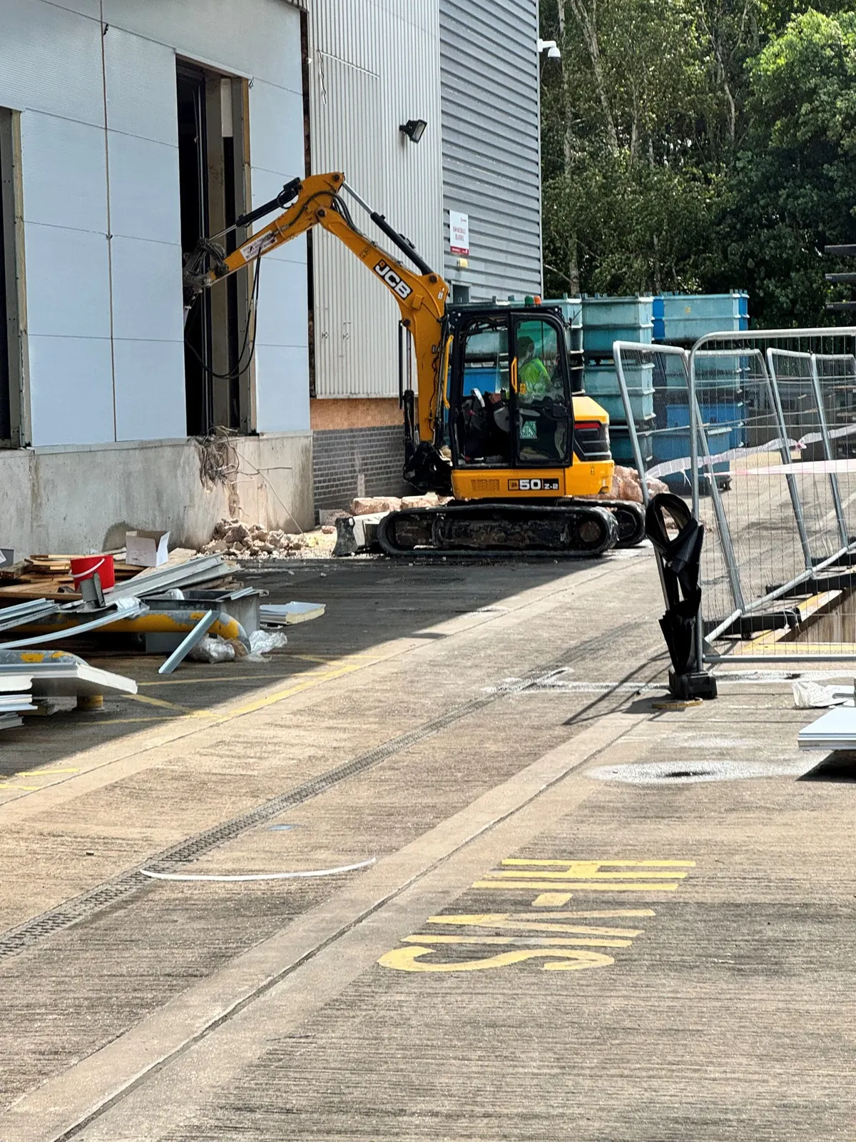Tracked excavator with a breaker attachment working at the base of the building elevation