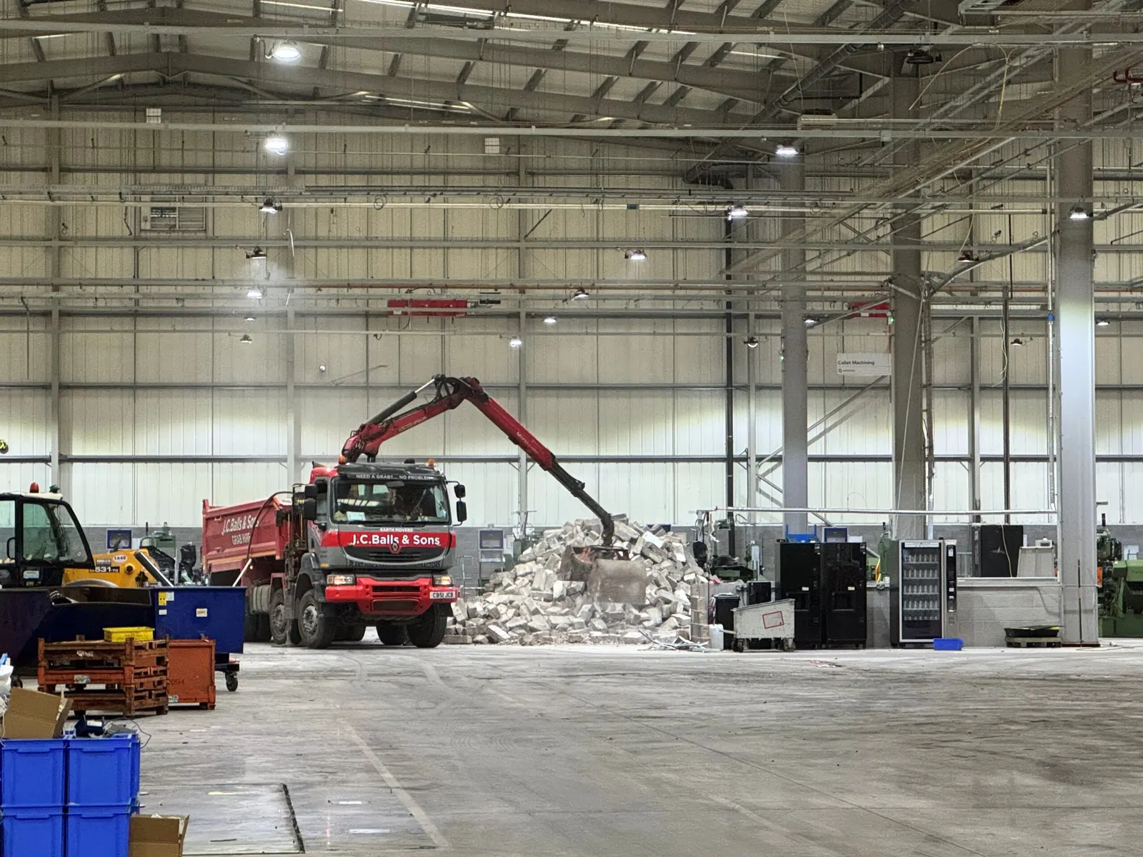 Grab lorry loading broken blockwork from the floor of the industrial hall