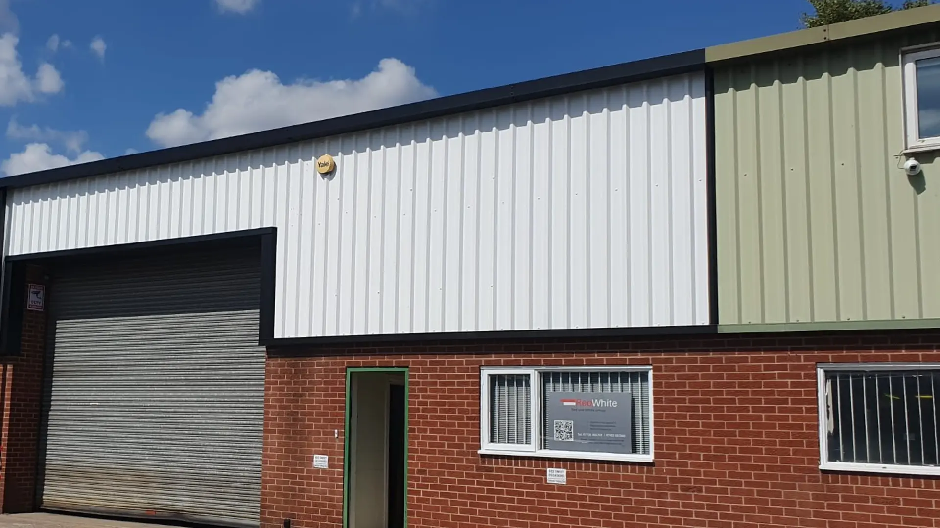Refurbished commercial unit in Burton-on-Trent with freshly coated white cladding and black flashings